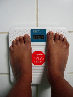 Image of someone weighing themselves on a scale