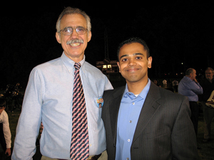 A photograph of a student posing with a teacher. The teacher is a middle aged man wearing a tie.