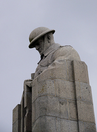 A photograph of a statue of a brooding soldier from World War I. He looks sad and is looking at the ground.