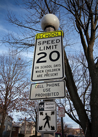 A photograph of a school zone sign that warns motorists not to use cell phones.