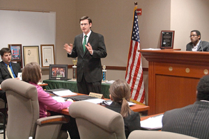 A photograph of a male lawyer arguing a case before a jury in a court room