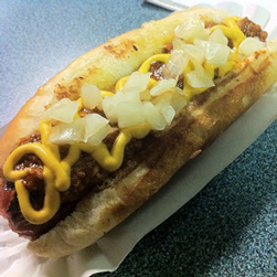 A photograph of a chili cheese hot dog with mustard and onions