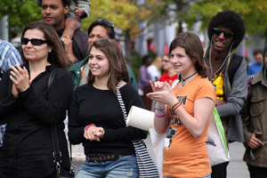 A photograph of several high school students and adults standing together and applauding