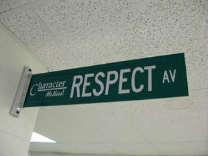 A photograph of a street sign in a hallway. The sign reads “Character Matters: Respect Avenue.”