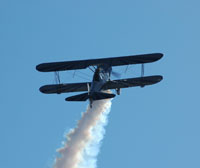 Image of stunt plane in the sky with vapor trails behind it.