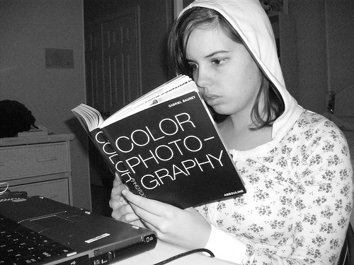 Black and white image of a young female reading a book.