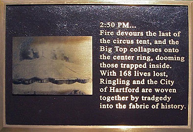 Plaque commemorating victims of a 1944 fire in Hartford, Connecticut. It has a bronze-colored picture of a circus tent, and the caption reads 2:50 PM…Fire devours the last of the circus tent, and the Big Top collapses onto the center ring, dooming those trapped inside. With 168 lives lost, Ringling and the City of Hartford are woven together by tragedy into the fabric of history. Tragedy is spelled T-R-A-D-G-E-D-Y
