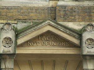 A photograph of an engraving on a building that reads, 'facts not opinions.'