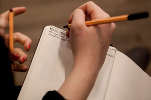 A photograph of a female student writing in a notebook.
