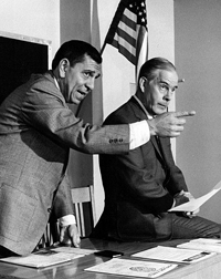 A photograph from the television series Dragnet. It shows the character Joe Friday and his partner, Bill Gannon in a courtroom. 