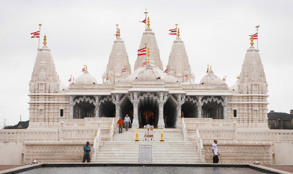 Image of a large Hindu Temple; several people are walking to and from the temple