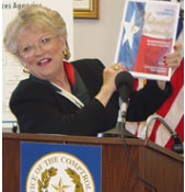 Image of Carole Keeton Strayhorn, smiling and holding up a document