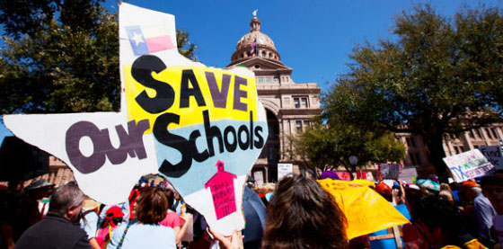 Image of protesters holding up signs in front of the Texas state capitol