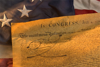 Old parchment paper on top of an American flag with a pair of eyeglasses on the paper. 