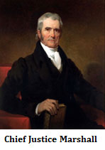 A portrait of a middle aged man seated on a red chair wearing a black suit and holding a brown-leather bound book.