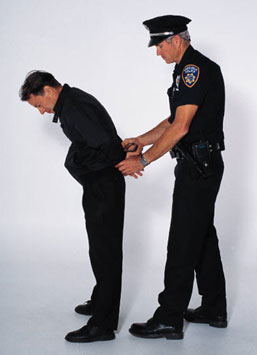 A police officer in a blue uniform handcuffing a man