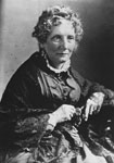 A portrait of an older woman in a dress with curly hair.