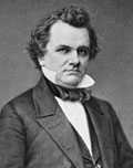 Portrait of a man with wavy hair wearing a black suit, dress shirt with upturned collar and a closely tied string tie