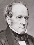 Portrait of a man with balding hair wearing a dark suit, white dress shirt and a closely tied string tie