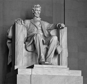 A large marble statue of a man seated in a chair on a pedestal looking out into the distance