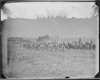A line of soldiers behind a few canons in an open field