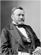 A seated man in a suit with a neatly trimmed beard