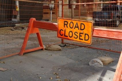 Image of a road closed sign enclosed by a gate that closes off a street
