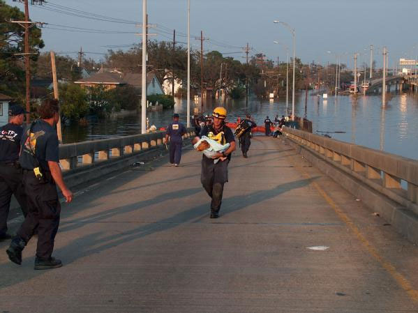 Image of an emergency worker carrying an infant out of flood waters.