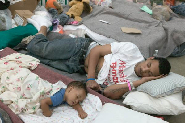 Image of a man and a baby sleeping on bedding on the floor of the Astrodome.