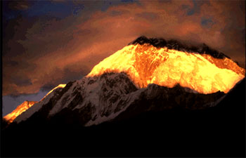 Image of Mt. Everest that is snow-covered, but looks like lava because of the sunset.