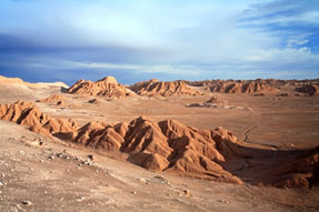 Image of a desert landscape surrounded by a mountain range. 