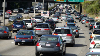 Image of a crowded highway filled with four lanes of cars and trucks