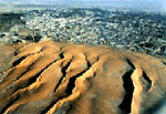 Image of very dry dunes that sit above a city Mauritania.
