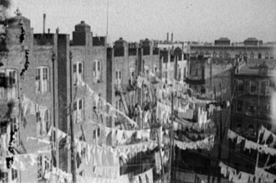 Image of several tenements buildings. There are clotheslines connecting several of the buildings.