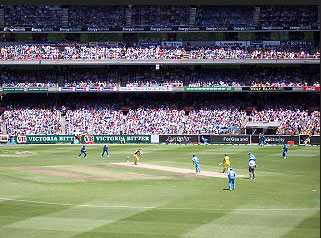 Image of a game of Cricket being played in a large stadium
