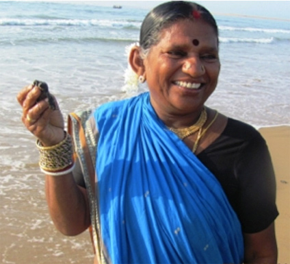 Image of an Indian woman holding a sea turtle while standing on the beach