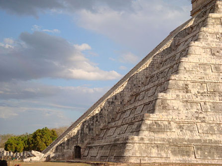 A side view of one of the great Mayan pyramids at the Chichen Itza site in Mexico. It is a large stepped structure with a stairway built into the front that resembles a serpent.