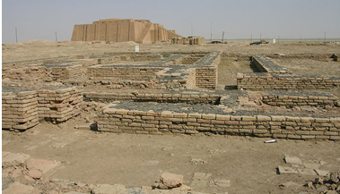 A photograph of an archaeological Dig at Ur featuring several partially unearthed structures near a ziggurat in the deserts of Iraq.