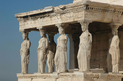 A photograph of statues of Greek women known as Caryatides that function as pillars for a roofed, balcony like structure.