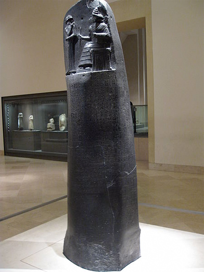 A photograph of the actual “Code of Hammurabi” inscribed on a large, standing slab of stone
