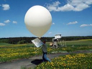 scientist holding weather balloon in a field