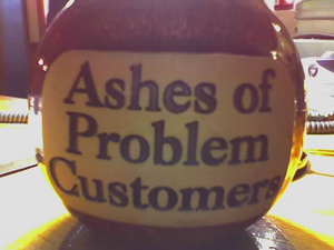 A photograph of a container with the words “Ashes of Problem Customers\” printed on it.