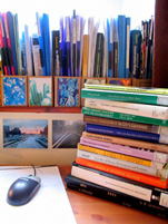A photograph of a pile of textbooks on a desk next to a computer mouse