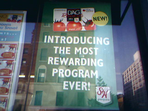  A photograph of sign in a store window that reads, “Introducing the most rewarding program ever!”