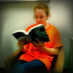 A photograph of a girl sitting in a chair reading a book