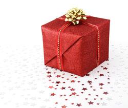 A photograph of a wrapped Christmas gift with star shaped glitter sprinkled around it