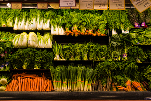 A photograph of a section of the vegetable aisle in a grocery store. There are radishes lettuces, parsley, carrots, and a variety of other vegetables