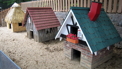 photo of three miniature houses built of straw, sticks, and brick