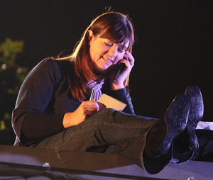 A young woman texting a friend at night. 