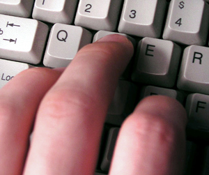A photograph of a person's fingers typing on a keyboard